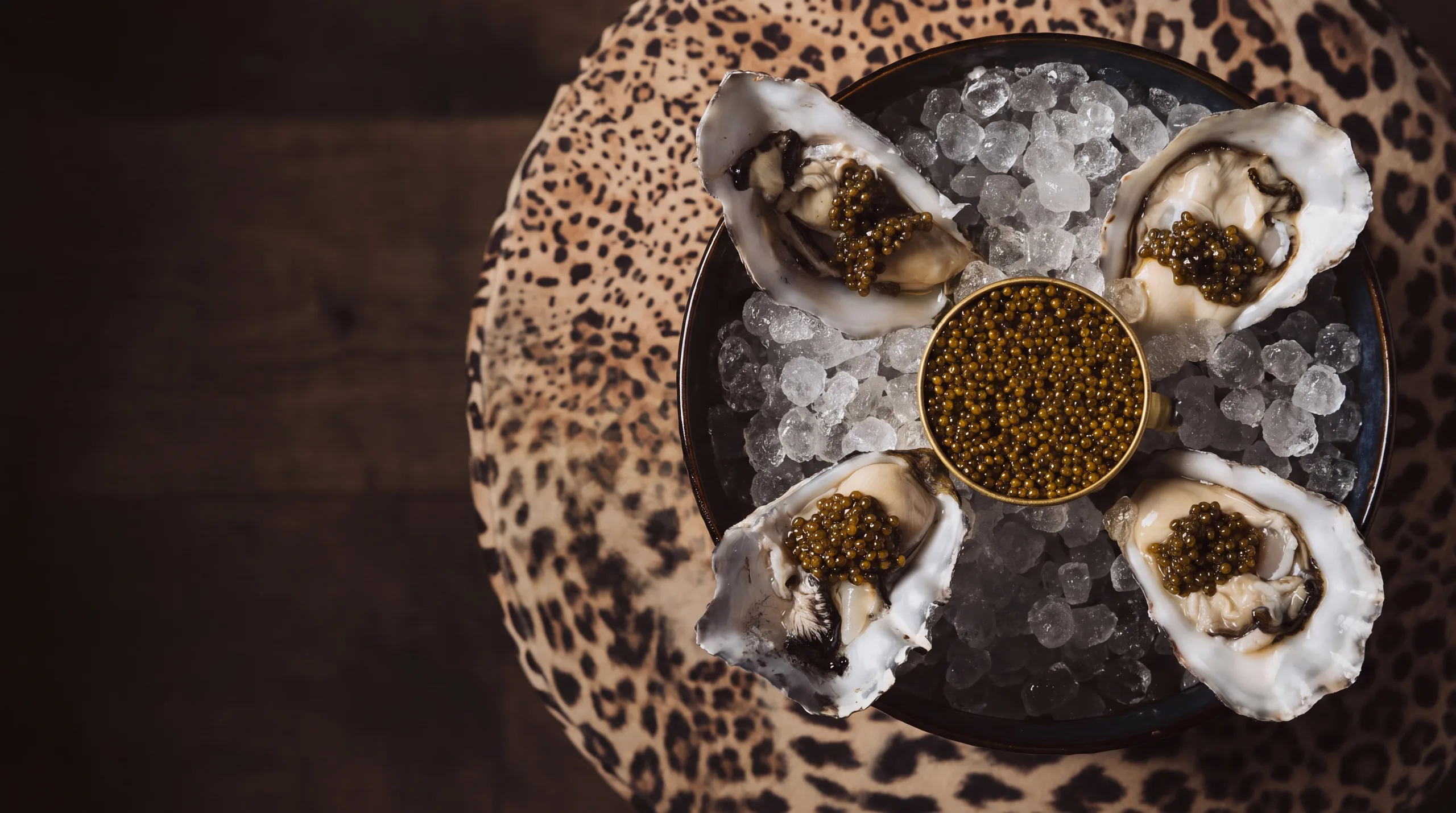 Oysters and caviar on ice over a leopard-print surface