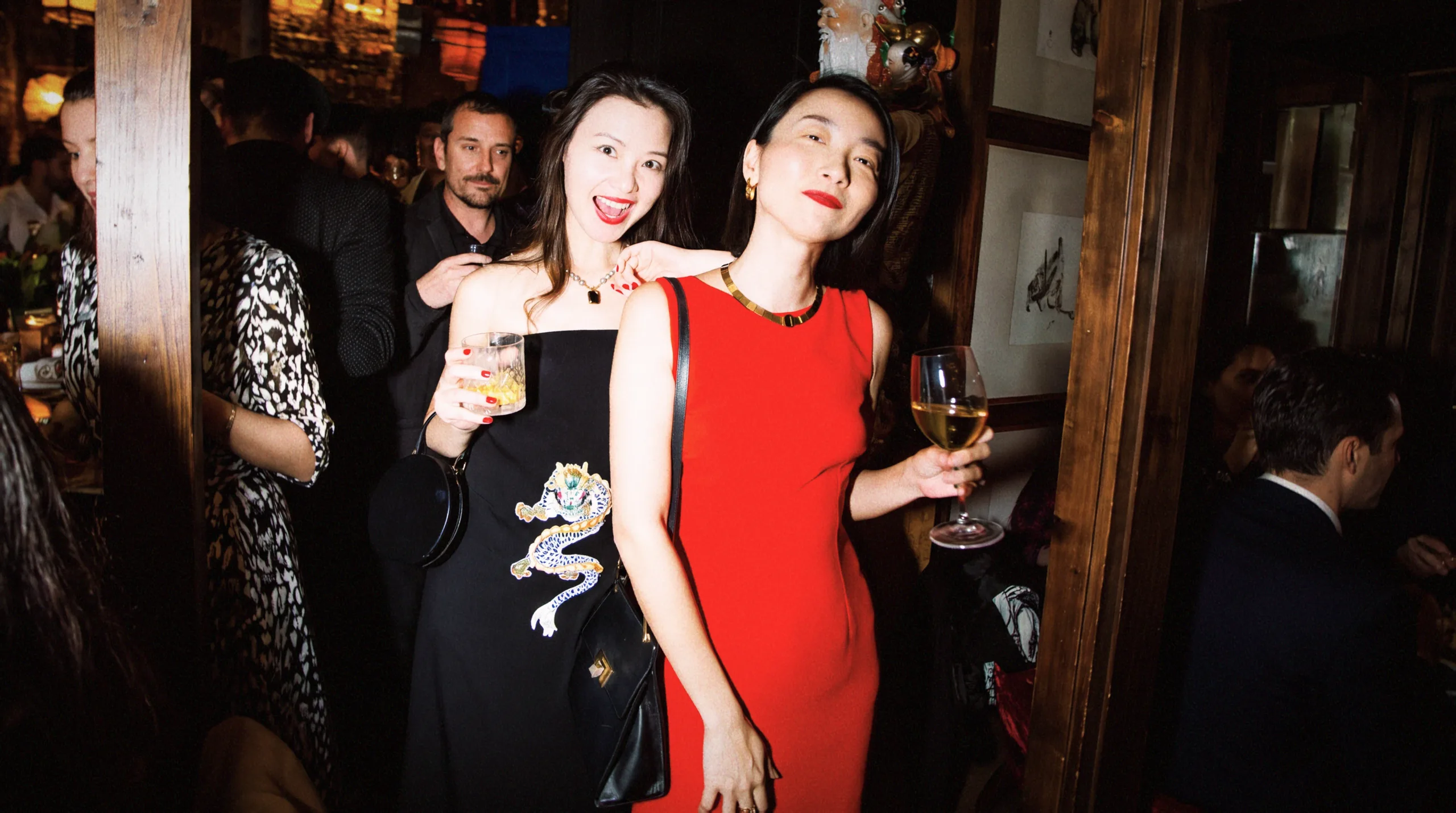 Two guests in a dragon-embroidered black dress and a red dress
