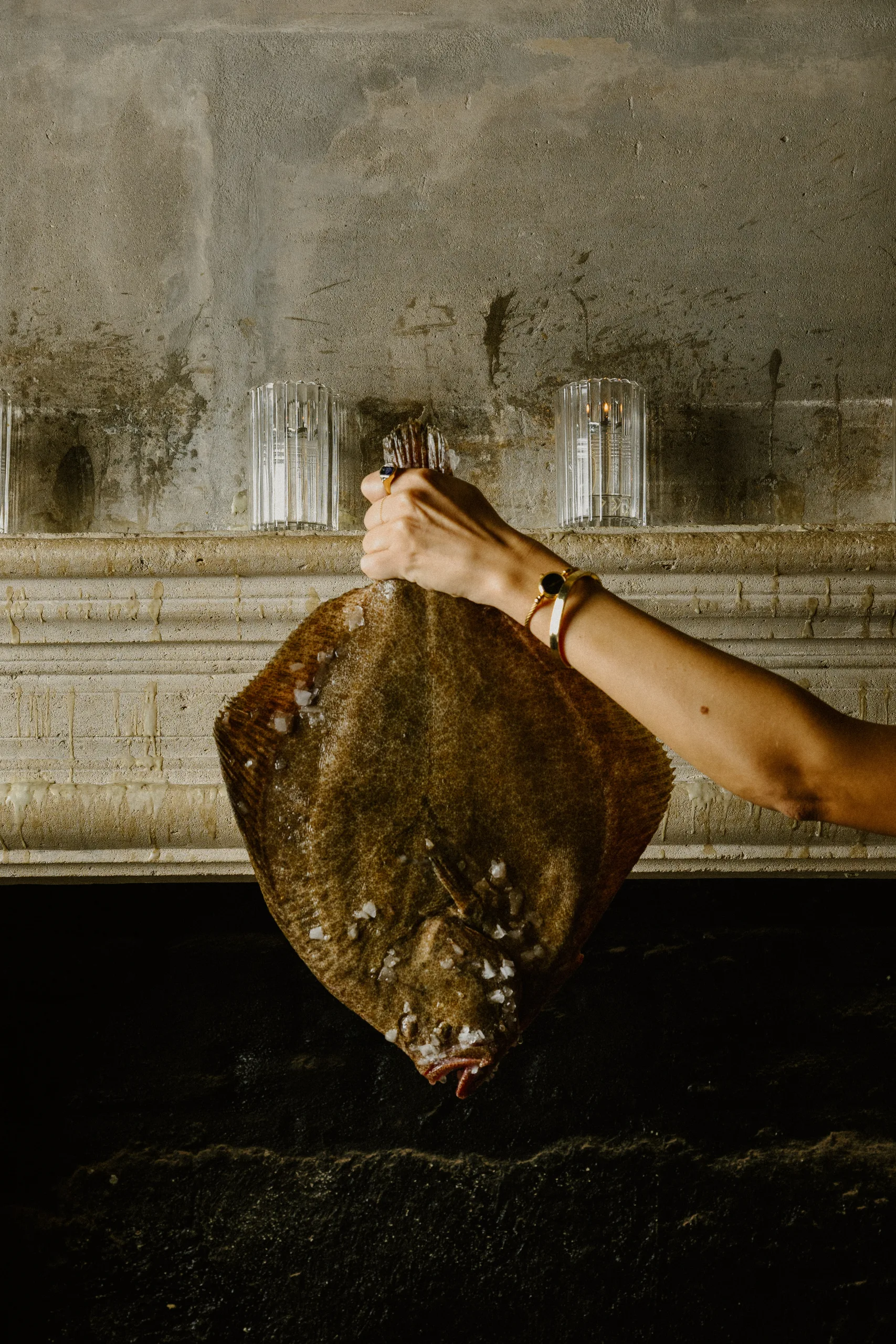 Salt-crusted flatfish held in front of the fireplace mantel